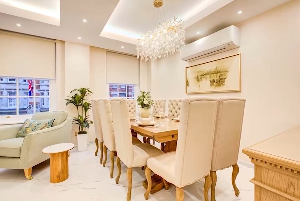 A dining room with tall upholstered chairs under a glass chandelier.